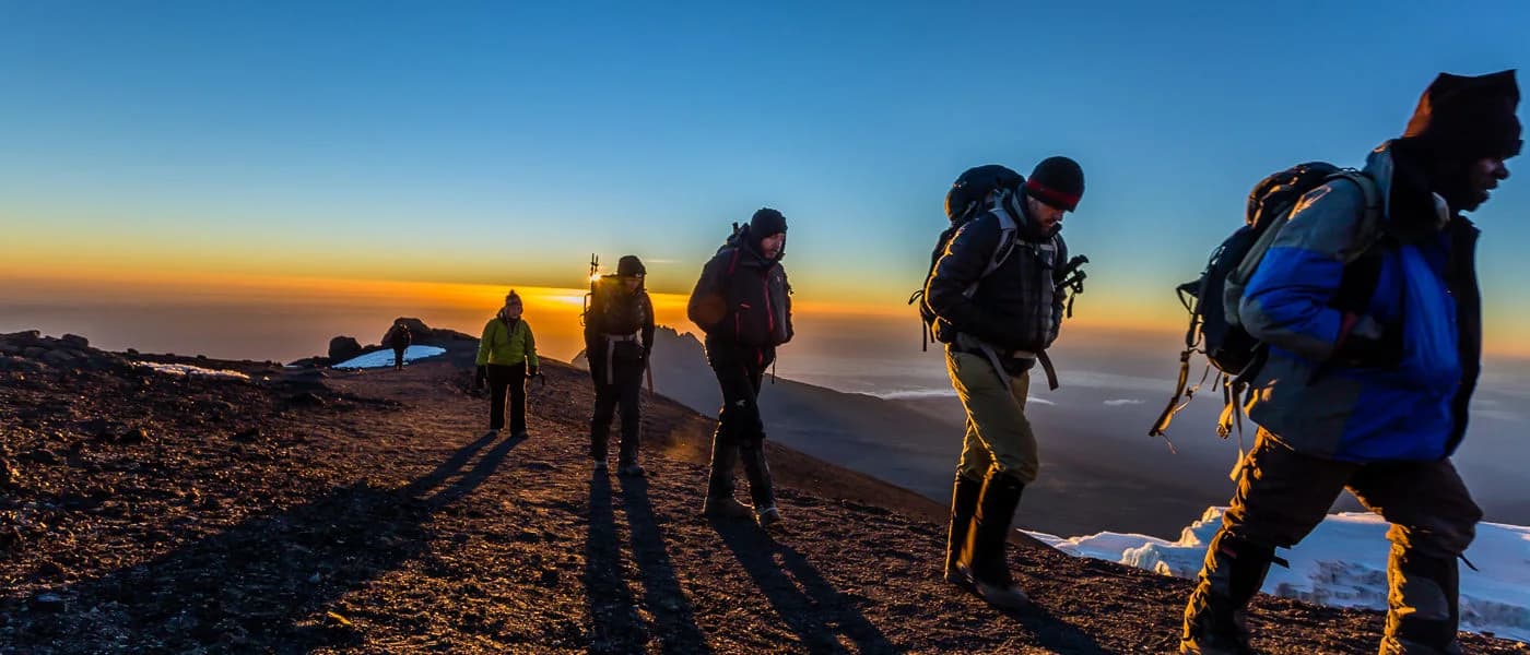 Trekkers walking across high mountain terrain at dawn