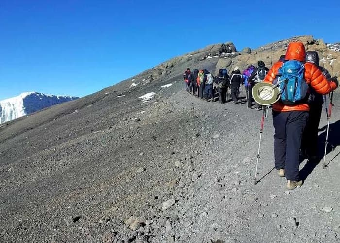 Trekkers ascending a grey rocky high-altitude slope