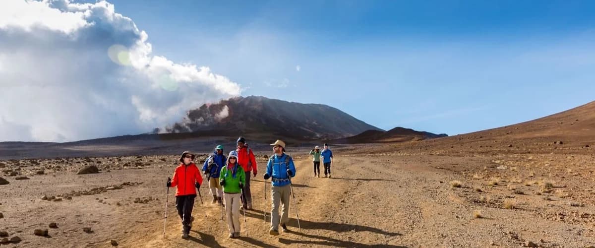 Trekkers crossing open brown mountain terrain beneath low cloud