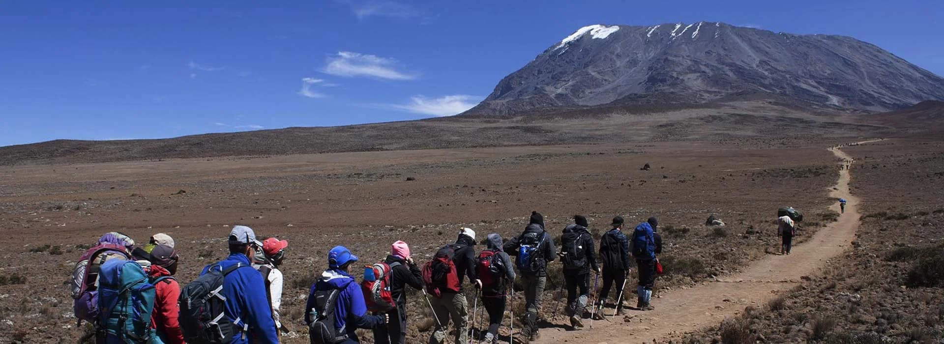 Line of trekkers crossing a broad dry mountain plateau